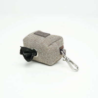 Elma poop bag holder dispensing a waste bag through its opening